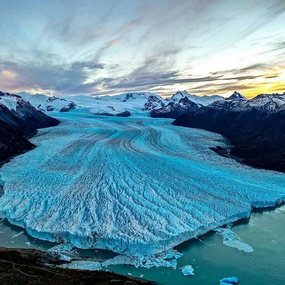 Vista aérea del Glaciar Perito Moreno al atardecer — el hielo azul de 30 km de largo y el Lago Argentino en tonos dorados