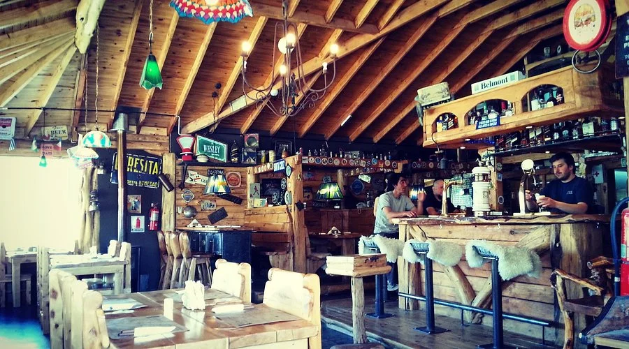 Interior rústico de La Cervecería El Chaltén — vigas de madera, barra y ambiente cálido
